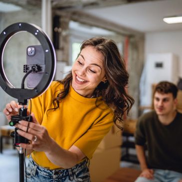 Woman adjusting ring light while a man watches in a cozy room.