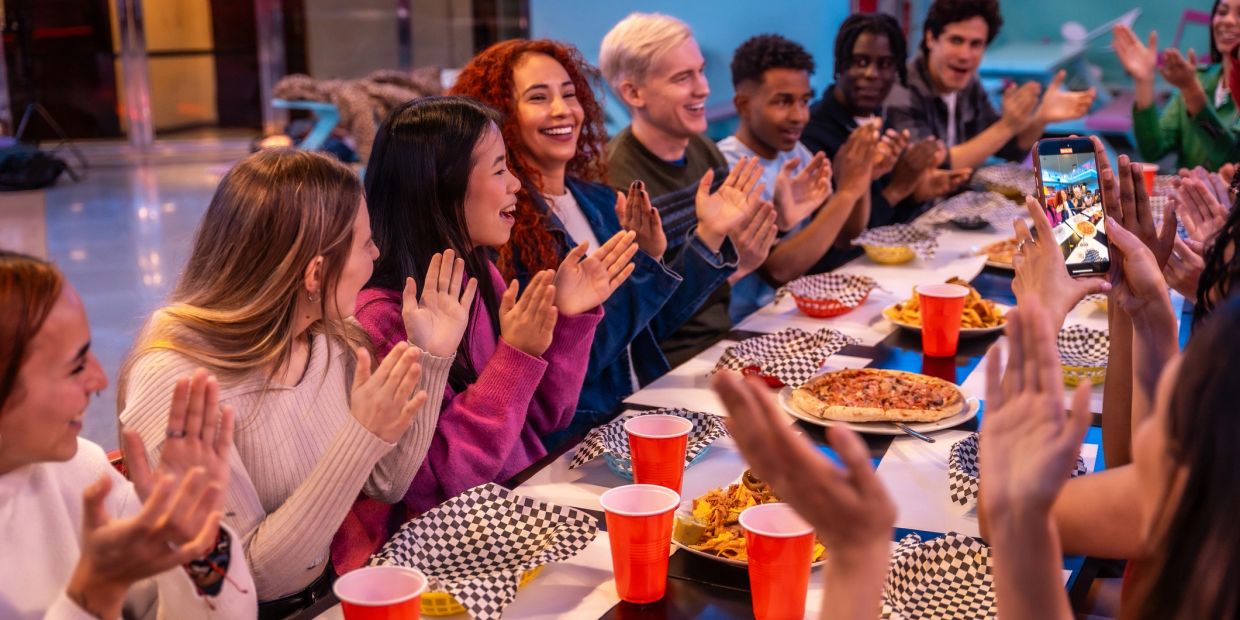 Friends clapping and enjoying food at a party.