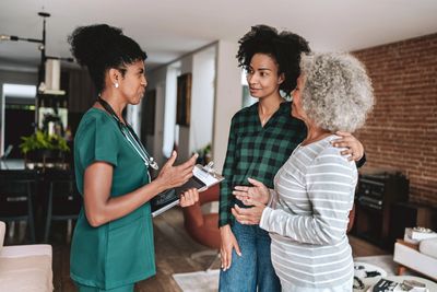 A nurse discusses health information with a mother and daughter at home.
