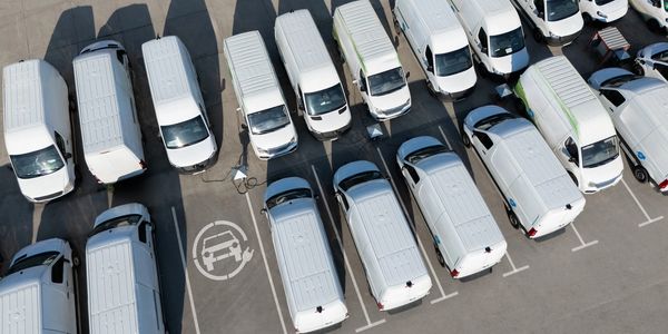 Aerial view of white vans parked in a lot.