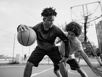 Two men engaged in an intense basketball game on an outdoor court.