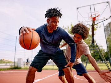 Two young men playing basketball outdoors.
