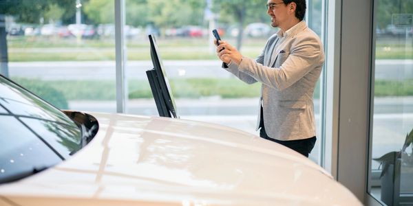 Man taking a photo of a white car inside a showroom.