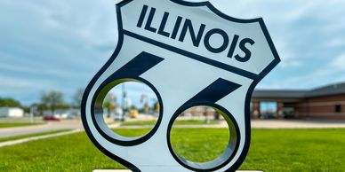 Illinois Route 66 sign with a scenic background.