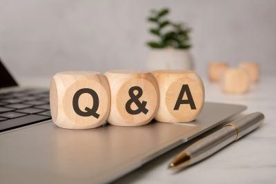 Wooden blocks spelling Q &amp; A on a laptop with a pen nearby.