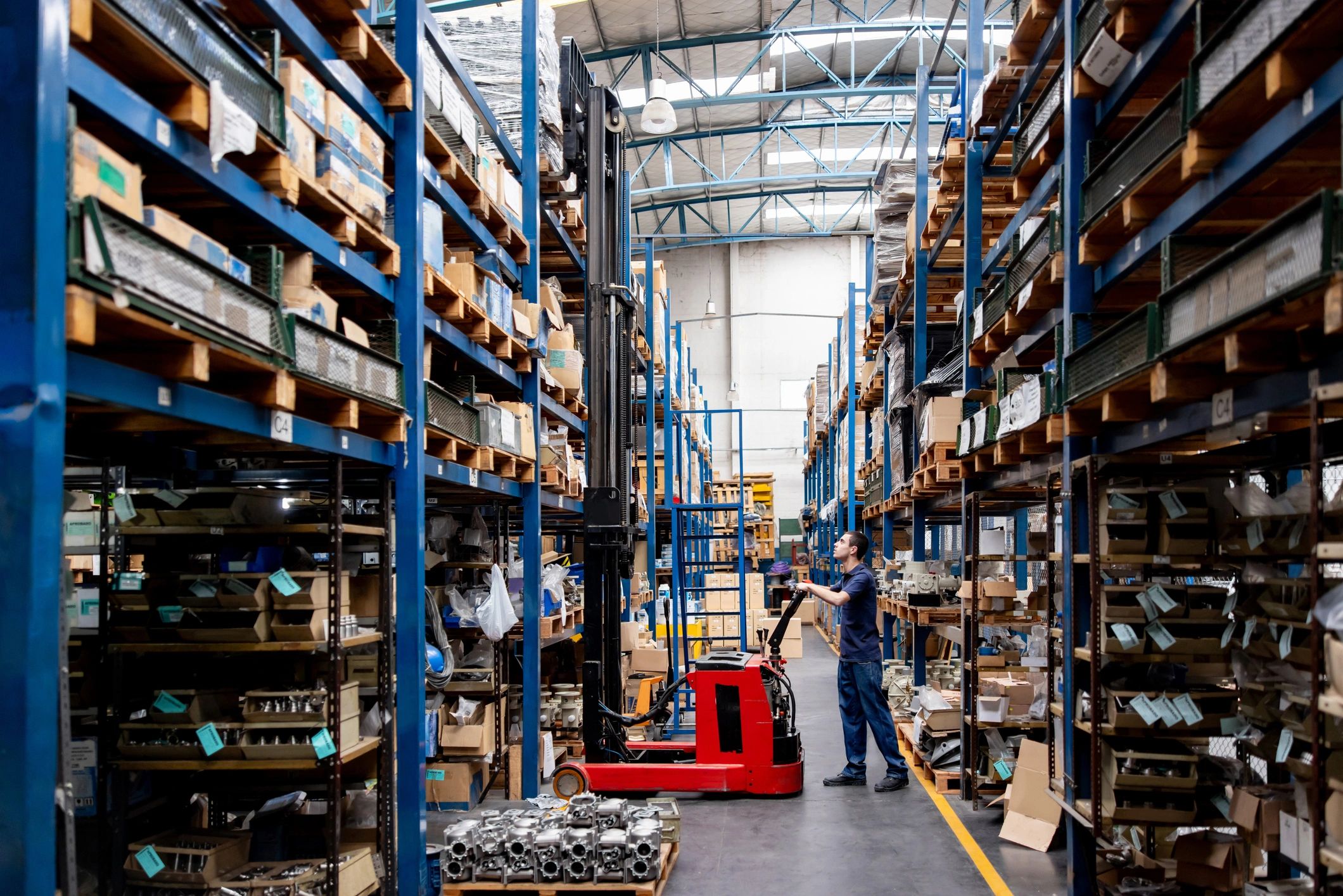 Man using forklift inside large industrial warehouse.