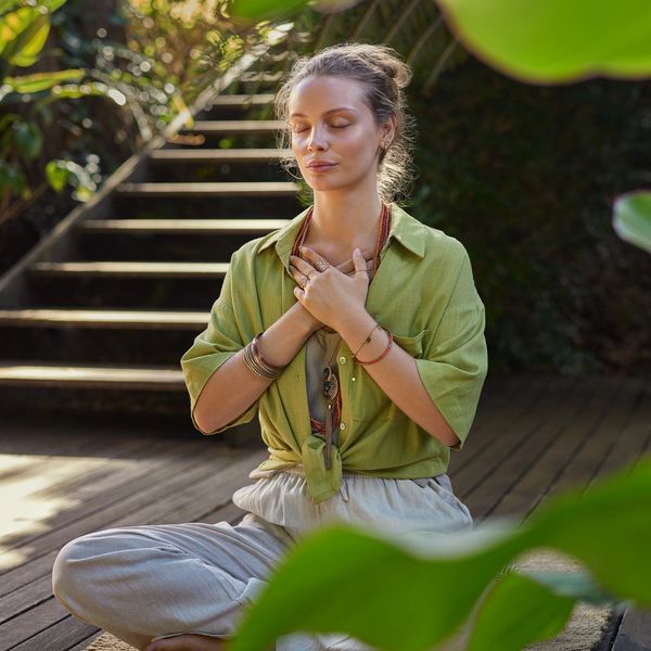 Woman sitting in meditative pose with hands on her heart