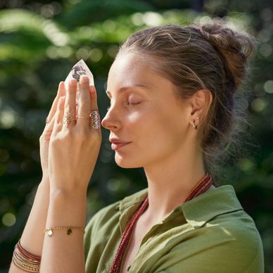 Woman meditating with a crystal in nature.