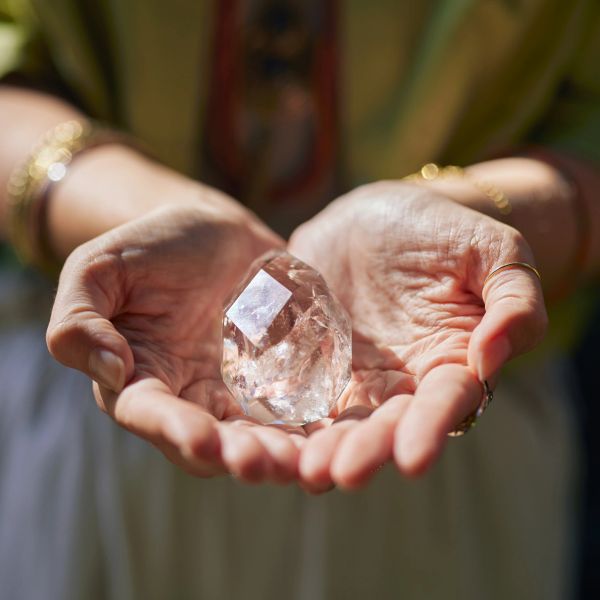 Hands holding a clear crystal.