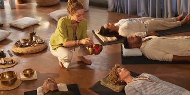 People lying down during a sound healing session with a facilitator.