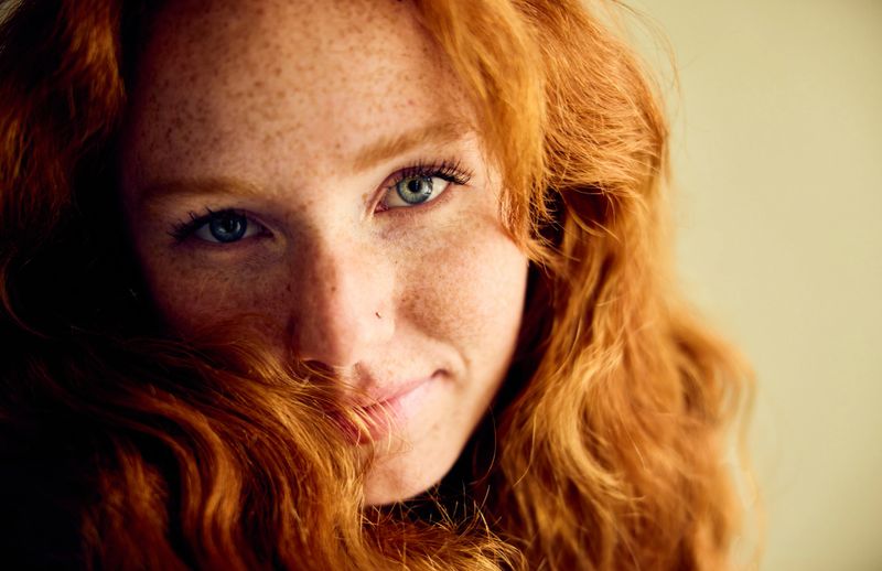 Close up portrait of woman in her 20s with red hair framing her face
