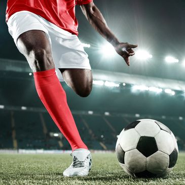 Soccer player in red and white about to kick a soccer ball on a stadium field.