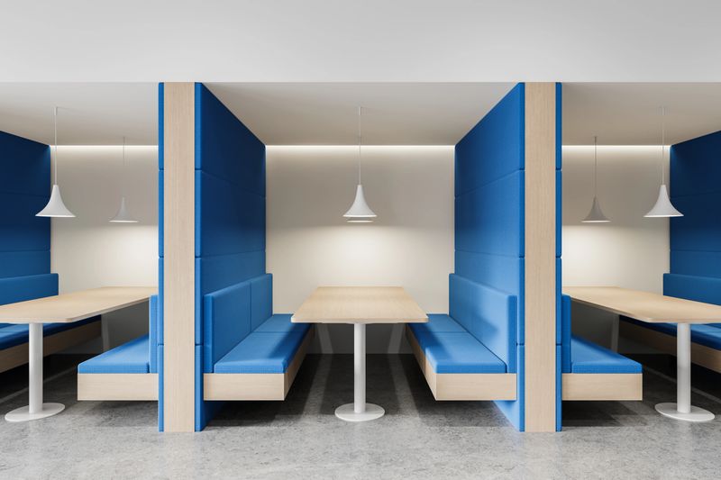 Contemporary office interior featuring blue padded booth seating with wooden tables and white pendant lights, set against a neutral background. 3D Rendering