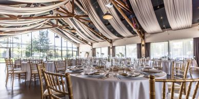 Elegant banquet hall setup with round tables and gold chairs.
