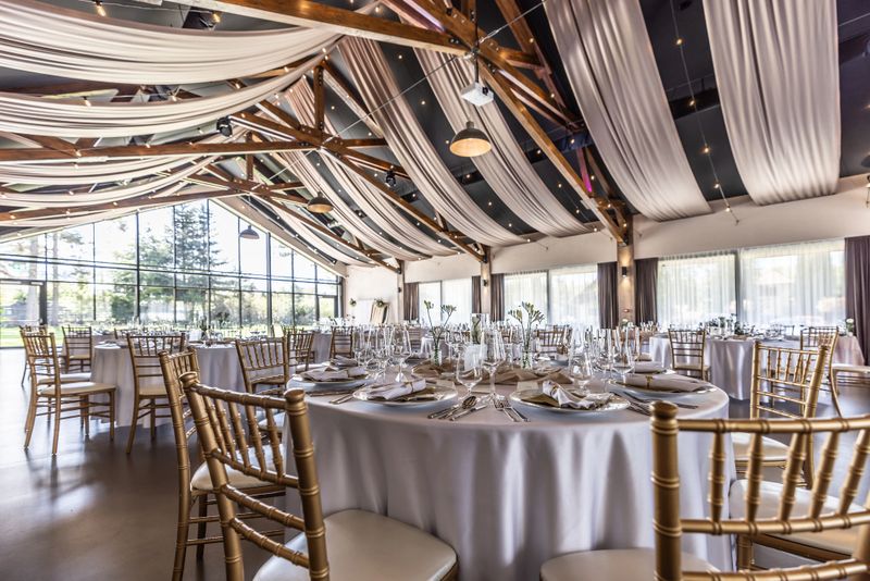 Wedding setting and decorated tables in a beautiful modern interior of a performance hall with a modern light ceiling of wooden construction.