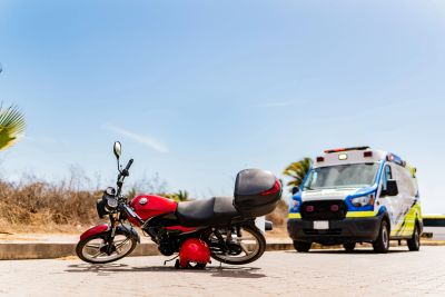 Red motorcycle with helmet and ambulance in background.