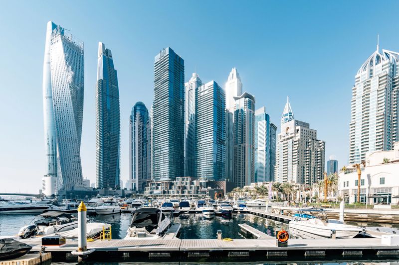 Modern cityscape of Dubai Marina with its iconic skyscrapers and a harbor full of yachts, reflecting the city's opulence and architectural prowess