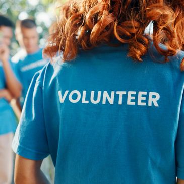 Person wearing a blue volunteer shirt with curly hair.