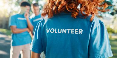 Volunteer wearing a blue shirt with others in background.