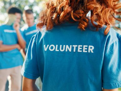 Volunteer wearing a blue shirt with others in the background.