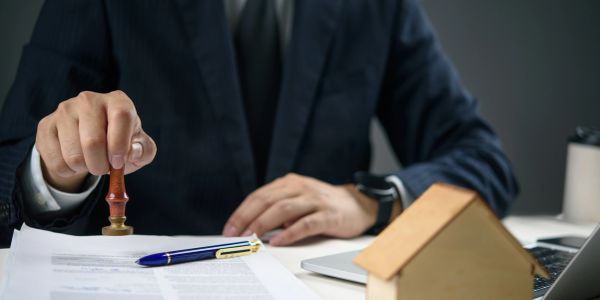 Person stamping a document at a desk with home model.