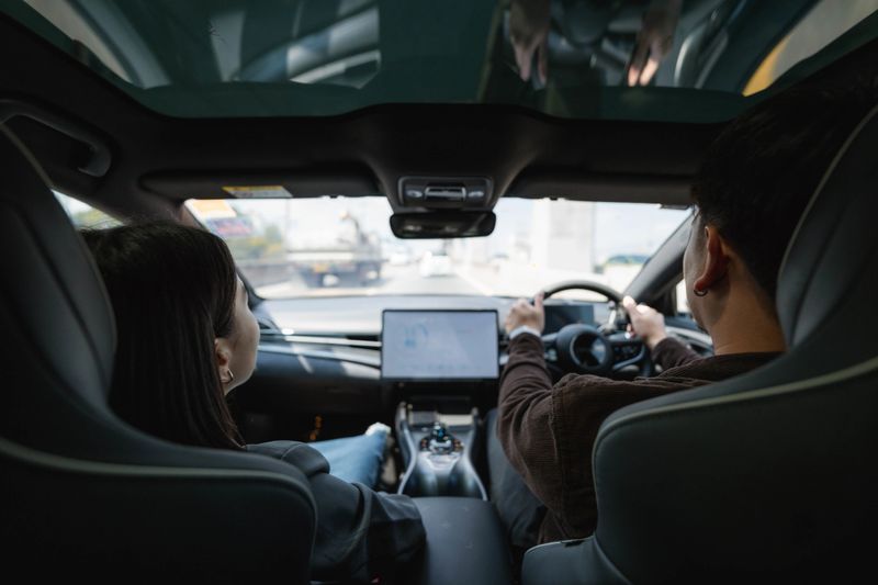 Man picking up his colleague in his EV car on the way to work, embracing a shared and eco-friendly commute. They greet each other with a smile, ready to start the day together