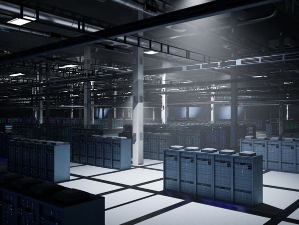 Large, dimly lit data center with rows of server racks and industrial ceiling.