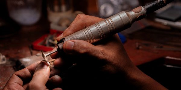 Hand polishing a small object with a rotary tool.