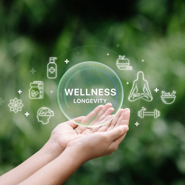 Hands holding a digital bubble with wellness and longevity icons.