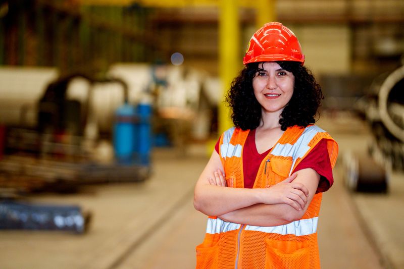Portrait of young beautiful engineer woman working in factory building, Female industrial construction worker in hardhat, occupational safety and health