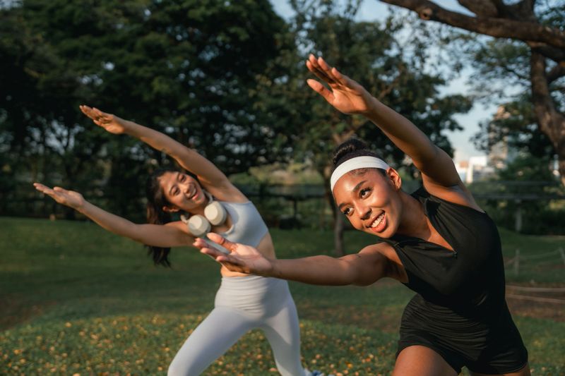 Two friends guiding each other through yoga poses, sharing laughter and encouragement as they bond over a rejuvenating and healthy session, strengthening both their bodies and their friendship
