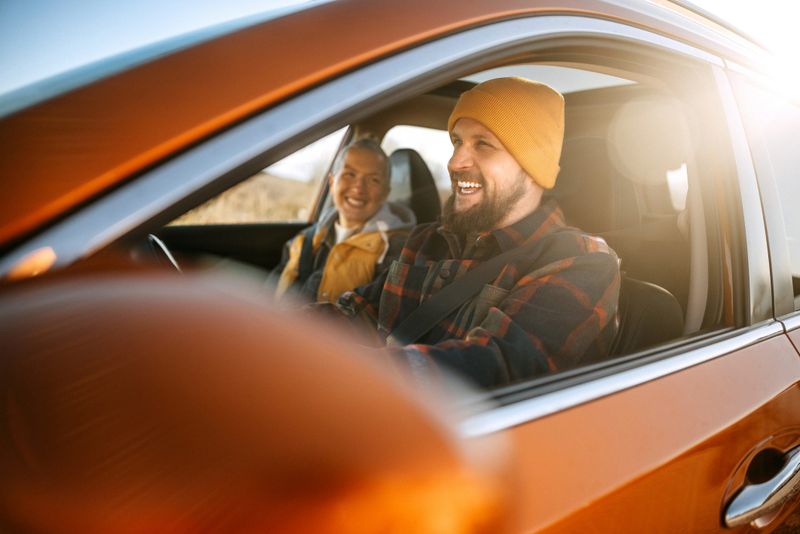 A happy couple rides in a car bathed in warm sunlight, smiling and enjoying the scenic journey as sunlight streams through the windows, creating a relaxed and joyful atmosphere