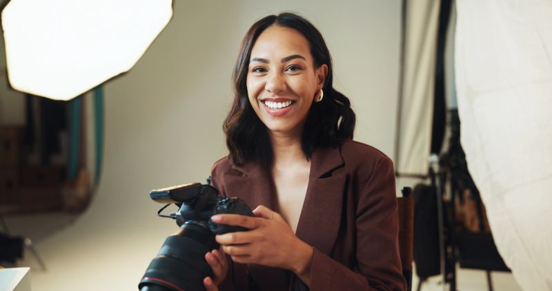 Happy, woman and photographer for portrait in studio of photoshoot results, catalog and selection. Smile, person or camera of photography career, film production and editing picture in media industry
