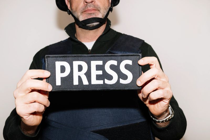 Reporter with bulletproof vest on white background.