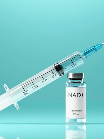 Syringe and NAD+ injection vial on a blue background.