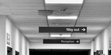 Signs in a hallway directing to the way out and reception.