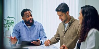 Three people discuss business in an office.