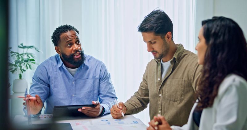 Group of business professionals meeting discussing financial strategy reviewing data on laptops and documents for market analysis at office. Finance meeting concept.