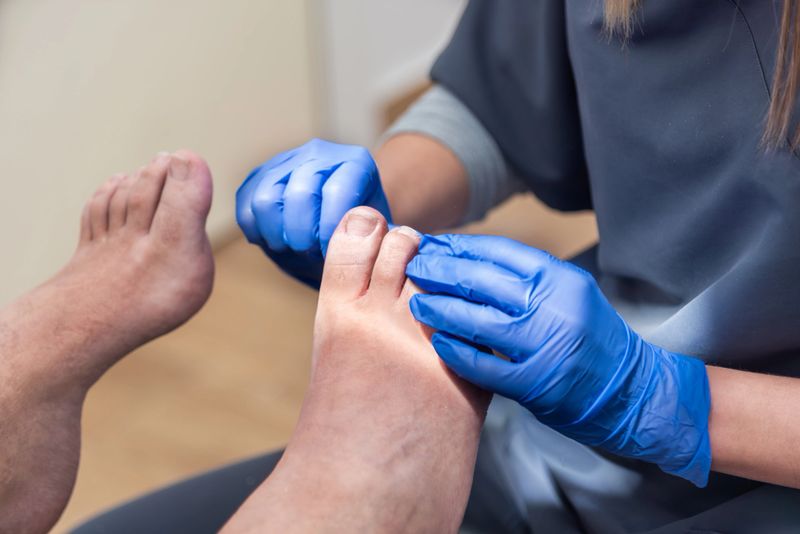 Podiatrist wearing blue gloves examining a patient's foot during a medical checkup, providing specialized foot care