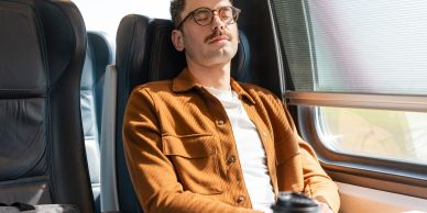 Hombre relajado en tren mirando por la ventana.