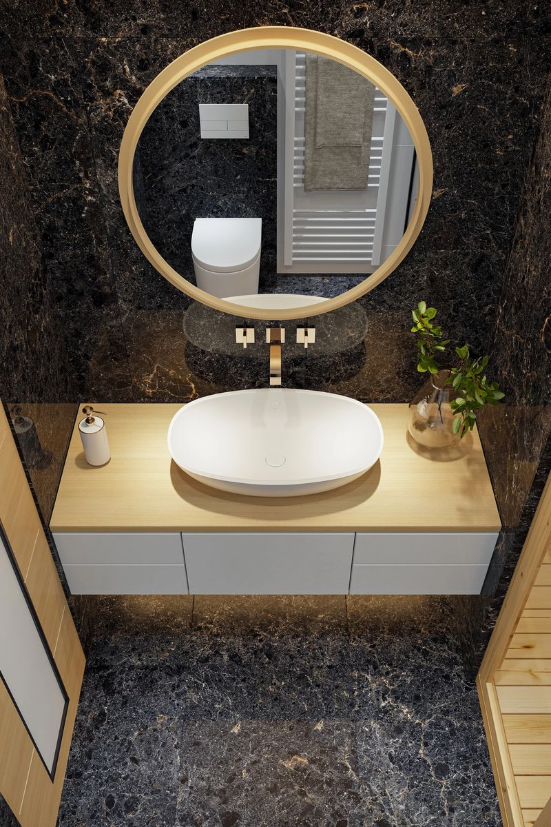 Stylish small bathroom featuring a two-person sauna crafted from natural pine wood, paired with glossy black marble tiles on the floor and behind the round mirror for a striking contrast. The blend of warm wood tones and sleek dark surfaces creates a luxurious, spa-inspired ambiance in a compact space. Ideal for showcasing modern wellness design, spa concepts, high-end bathroom interiors, and innovative space-saving architecture.