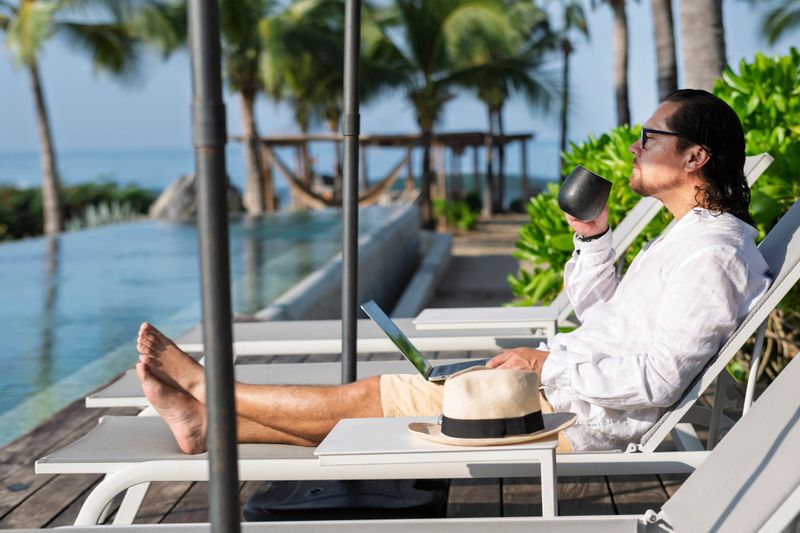 man working on computer on his beach vacation