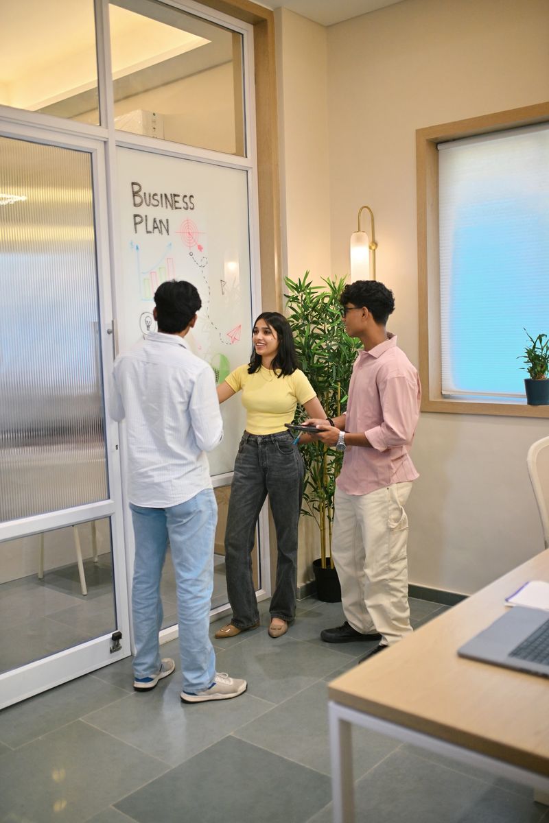 A group of young colleagues work together in a newly set up office, exchanging ideas and collaborating on projects. The environment reflects energy, innovation, and the spirit of teamwork in a fresh, modern workspace.