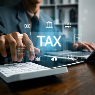 Person calculating taxes with a calculator and laptop.