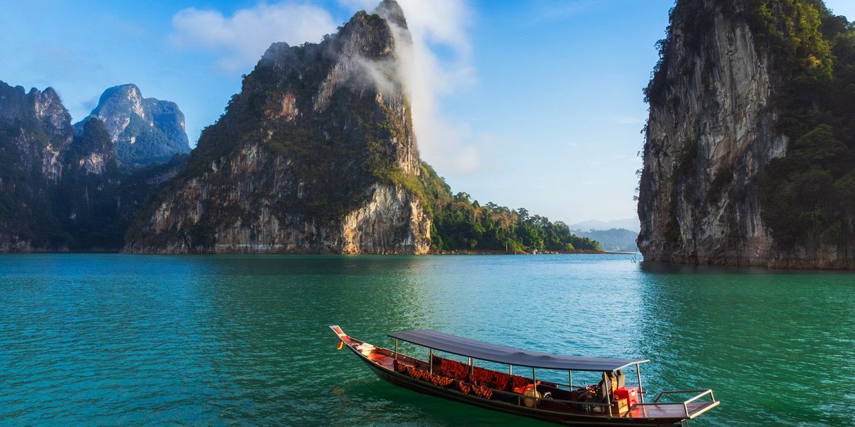 Boat sailing in turquoise water surrounded by tall rocky cliffs.