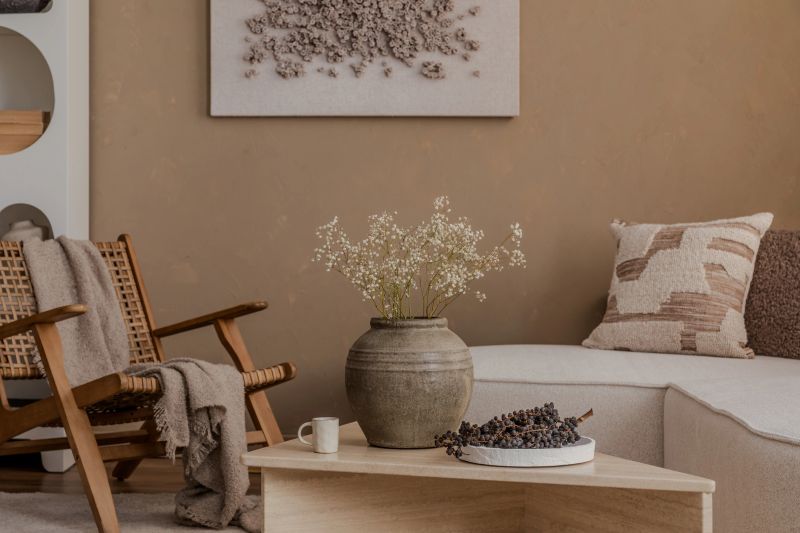 Natural-toned interior with rustic vase, textured pillows, and cozy lounge chair in a calm neutral palette.