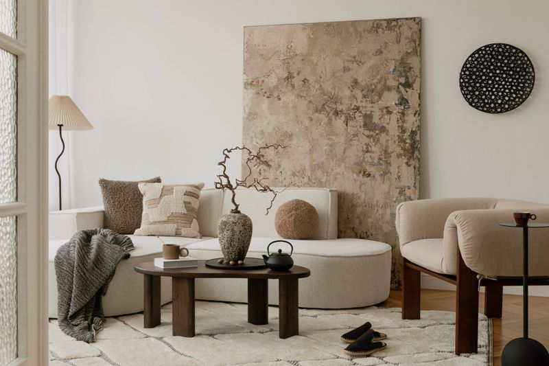 Bright neutral living space with textured pillows, soft boucle seating, and a ceramic vase as the focal point.