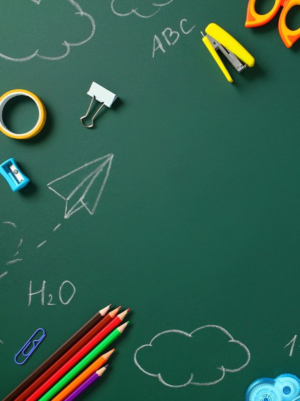 School supplies and chalk drawings on a green chalkboard.