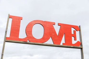 Large red wooden letters spelling LOVE against a cloudy sky.