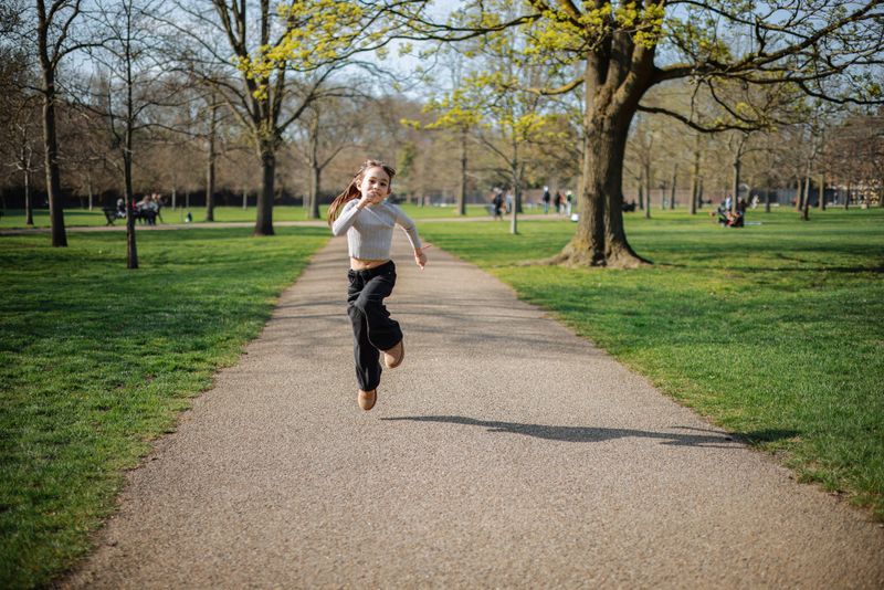 Playful child jumping in a sunny park during a photo shoot